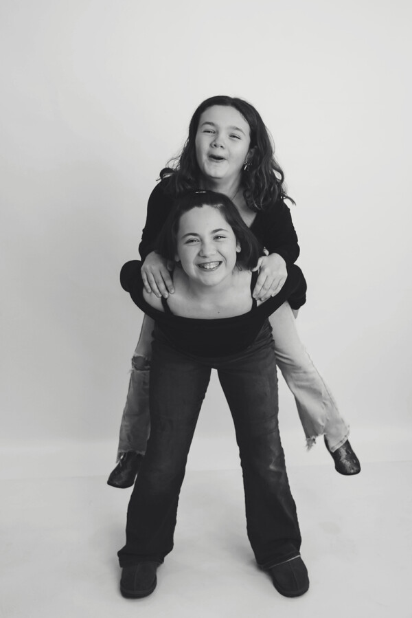 sister laughing and giving piggyback rides