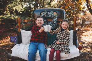 Siblings sharing cocoa mugs in front of holiday truck on the Yardley Canal.