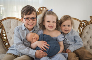 newborn being held by his siblings