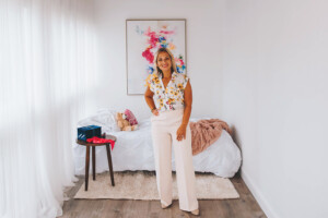real estate agent posed in front of a bedroom setup.