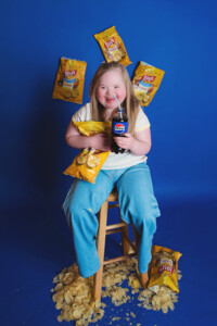 surrounded by Lay’s potato chips smiling during creative portrait session Bucks County PA