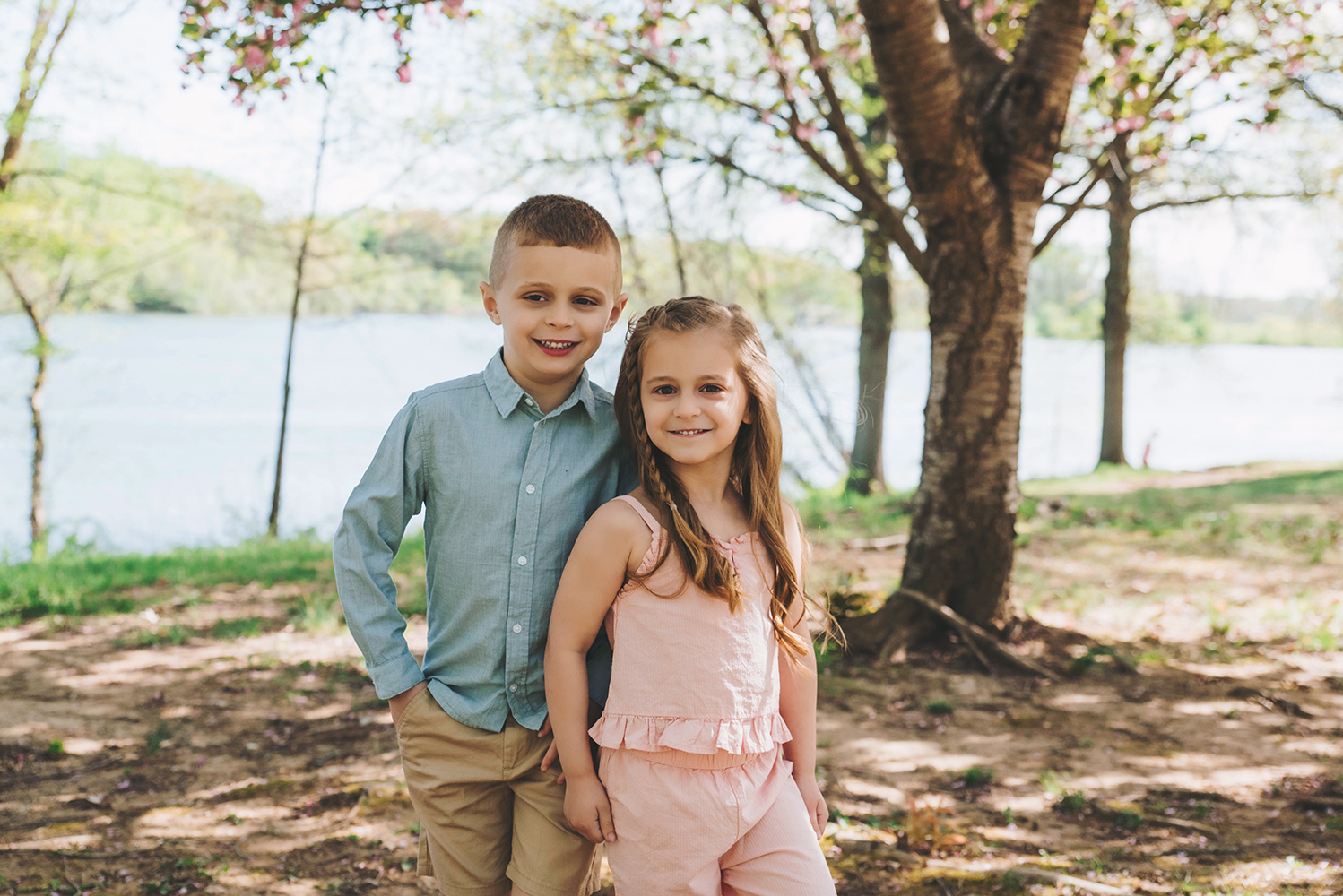 Two siblings laughing and running through tall grass at Core Creek Park during a spring family session