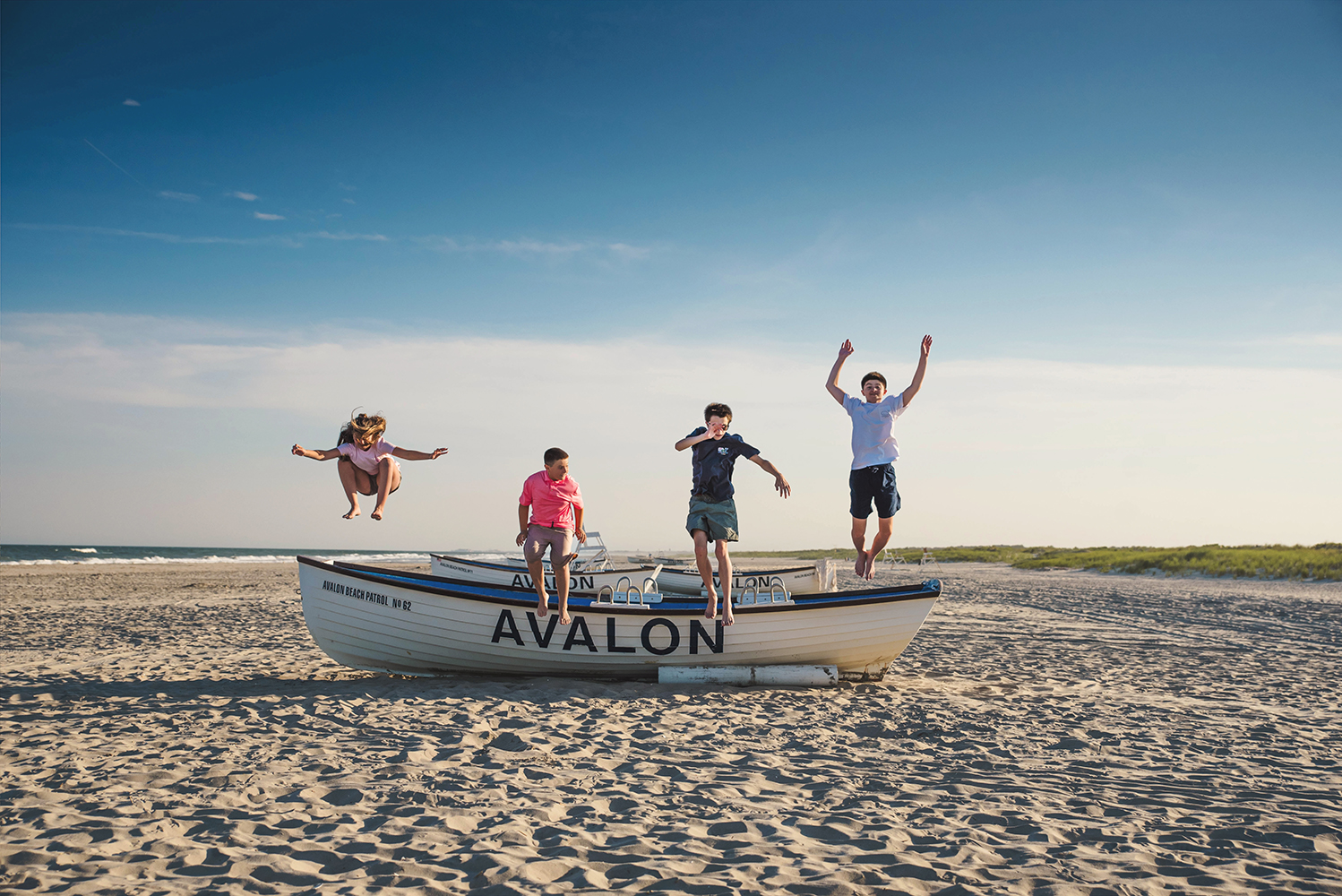 Children playing together on the beach during a summer family portrait session.