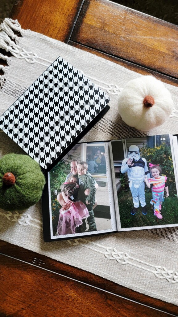 Open Halloween photo albums displaying children’s costume portraits, styled on a coffee table with fall decorations.